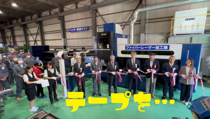 ファイバーレーザー加工機の導入記念テープカットで紅白のテープを持つ参加者