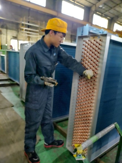 空調機器用の熱交換器コイルの拡管作業を行うスタッフ
